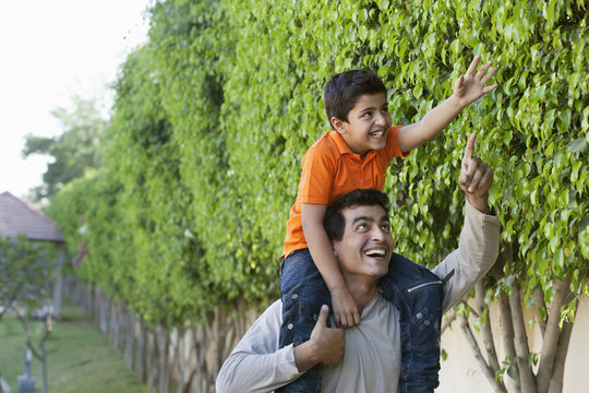 Father helping his son reach for a leaf