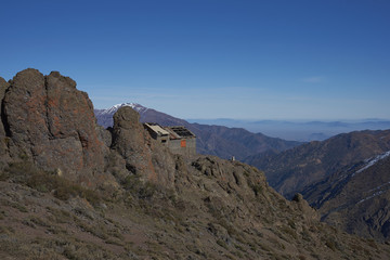 Derelict mountain hut, Refugio Alemana, in the mountainous landscape of Parque Yerba Loca set in a glacial valley close to Santiago, capital of Chile. Santiago in the distance under a layer of smog.