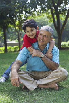 Grandson hugging grandfather in park