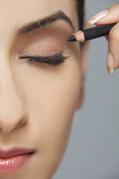 Beautiful woman applying eyeliner