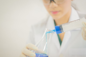 Young Asian scientist working in the lavatory with test tubes and other equipment to discover new drugs, products and methods of formulation