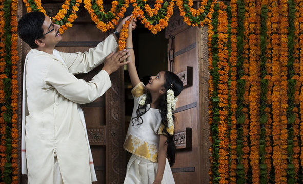 South Indian man helping his daughter decorate 
