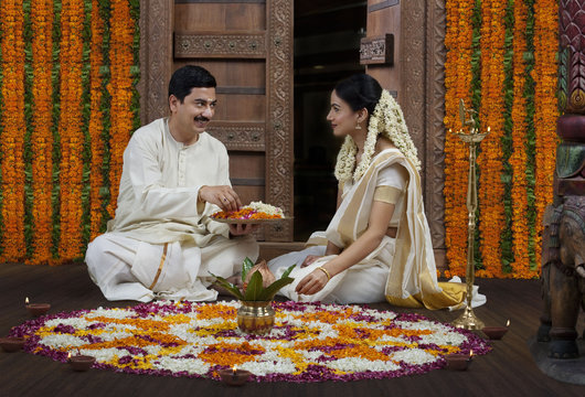South Indian couple with a flower rangoli 