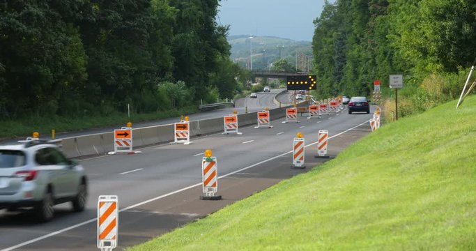 Cars navigate a closed lane in a road construction repair zone.  	