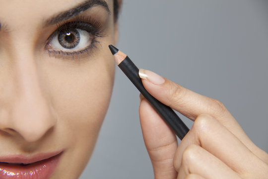 Beautiful woman applying eyeliner