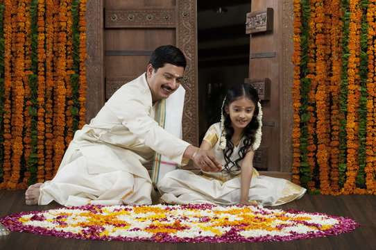 South Indian man and daughter making a rangoli 
