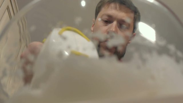 Closeup of a man pounding a mixer cream in a transparent bowl