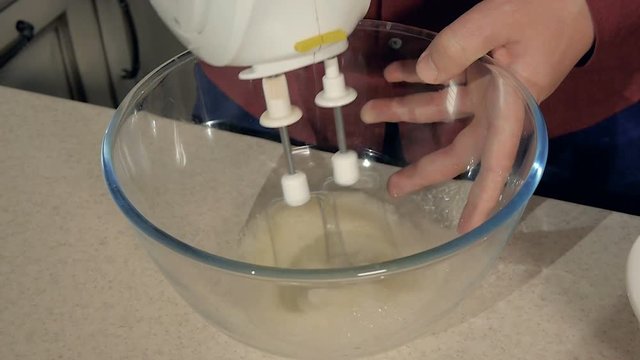 Closeup of a man pounding a mixer cream in a transparent bowl