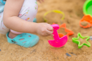 Fototapeta na wymiar Kid hand playing with plastic toy in sand box