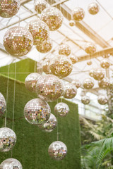 Disco ball hanging on ceiling under greenhouse in the sunlight