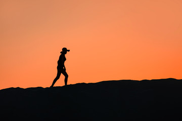 Silhouette of woman walking on the sand hill at sunset - Patara, Turkey