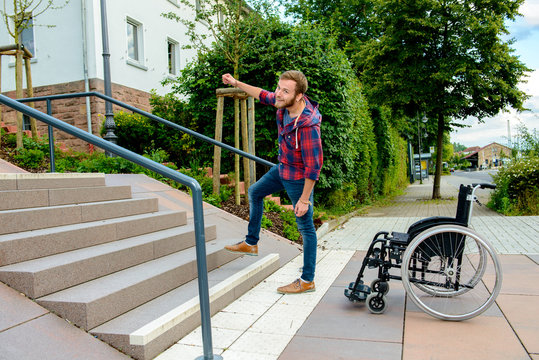 man standing with wheelchair in front of stairs