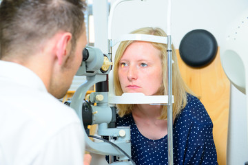 ophthalmologist checking eyes of woman for new glasses