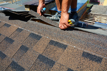 Repair of a Roofing from shingles. Roofer cutting roofing felt or bitumen during waterproofing...