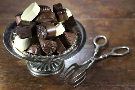 belgische Schokoladenpralinen in einer Silberschale auf rustikalem Holztisch