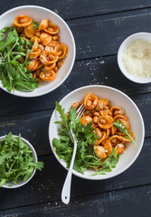 Pasta with beans, tomato sauce, parmesan and arugula on dark background, top view. Vegetarian beans orecchiette pasta