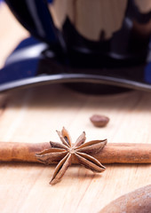 Cinnamon and anise by a coffee cup on wooden surface