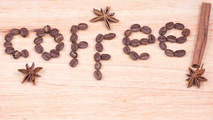 Coffee word written with beans and cinnamon and anise on a wooden surface