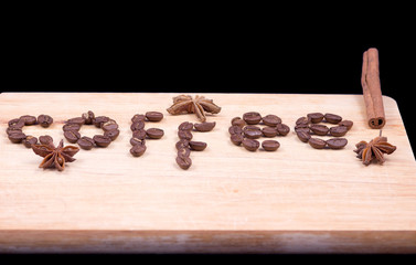 Coffee word written with beans and cinnamon and anise on a wooden surface