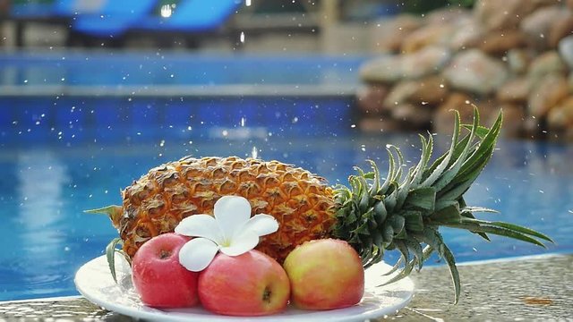 A splash of water dropping on a fruits Pineapple and Rose Apple and frangipani flower on the back of Swimming Pool in slow motion. Fresh Breakfast in Thailand. 1920x1080