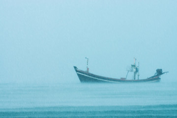 Fototapeta premium Fishing boat on the sea with raining in the sea.