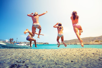 Group of friends jumping to the sea from the pier, happy beach holidays, Crete, Greece