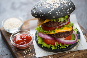 Closeup of black double beef burger on a wooden serving board, selective focus, shallow depth of field, studio shot