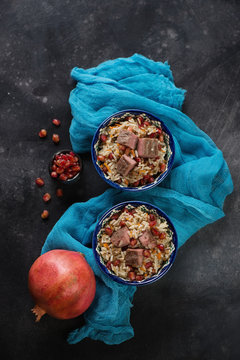 Pilaf cooked in georgian style with beef meat and pomegranate. Flat-lay on a dark metal background