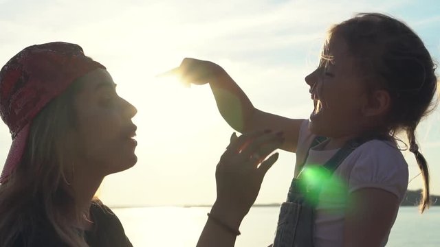 Mom and daughter have fun together. Daughter puts a baseball cap on her mom and laughs