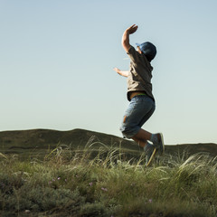 Fototapeta premium Boy Jump in grass in background of the hills