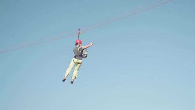 Woman riding on zipline on sunny summer day