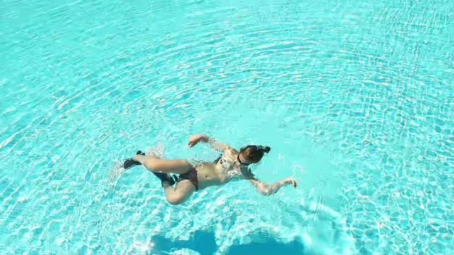 Teen girl swims in pool, slow motion