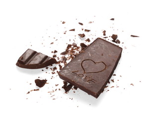 Chopped chocolate bars with carved heart isolated on white background