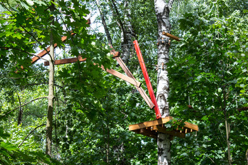 Fototapeta premium Elements of a rope town built into the city park. Elements of the tourist trail in the city park. Ecological hiking trail. Selective focus.