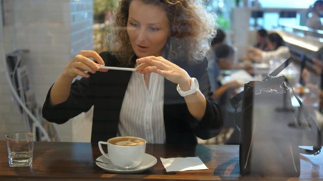 Woman Taking Picture Of Cup Of Coffee With Mobile Phone In Cafe. 4K. 