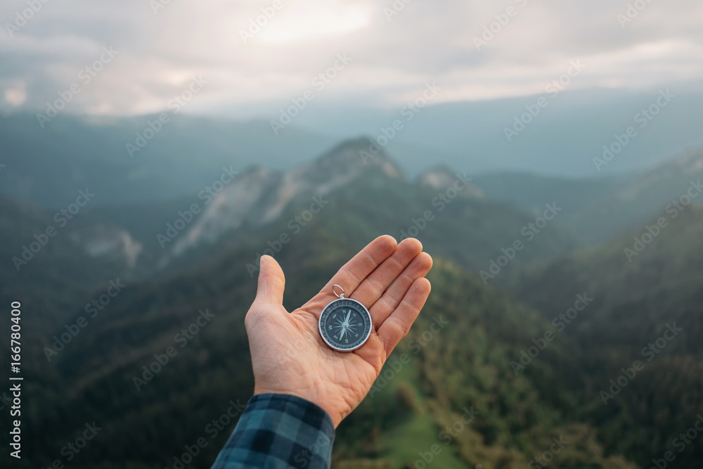 Sticker hand with compass in the mountains.