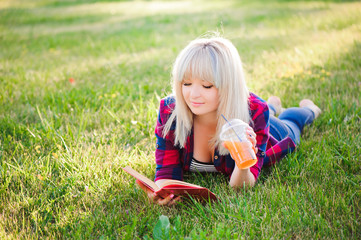 Fototapeta premium Girl drink juice and read a book in a park
