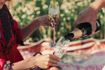 Guy pours champagne in a glass at a picnic