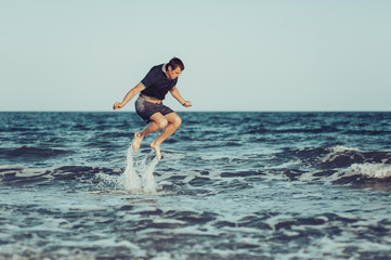 A young man is jumping and having fun in the sea