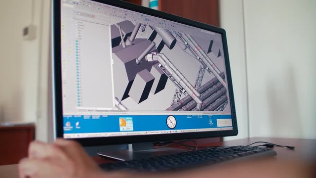 Rear view of engineer worker sitting and making 3d model on pc