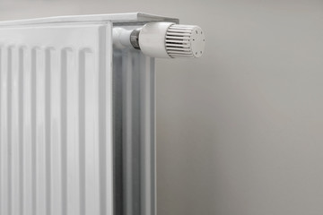 Home insulation.Economical house heating system.
Horizontal frame with a place for an inscription on a light background Fragment of a radiator for water heating in an apartment with a heat regulator