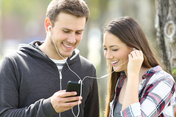 Happy couple of teenagers sharing music