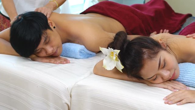 dolly shot of young couple having simultaneous body massage in spa