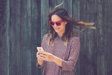 Portrait of young female using smartphone against wooden wall