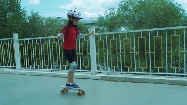 The girl skates on skateboard. The child learns to skate.