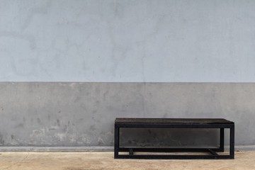  steel long bench in front of dirty gray old wall