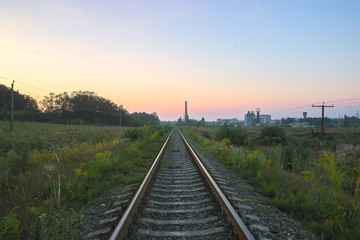 Fototapeta na wymiar railroad near high voltage power lines at dramatic sky
