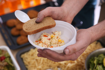 Hands of poor man holding bowl with rice and bread. Poverty concept