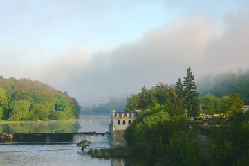 Fototapeta na wymiar Old rusty dam on a river at cloudy sky