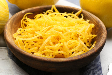 Bowl with fresh lemon zest on table